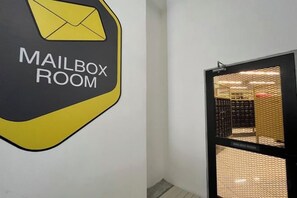 A hallway with a sign indicating a mailroom and a door leading to a room with a mesh partition. - Arte Cheras by Awesomestay (Kuala Lumpur)