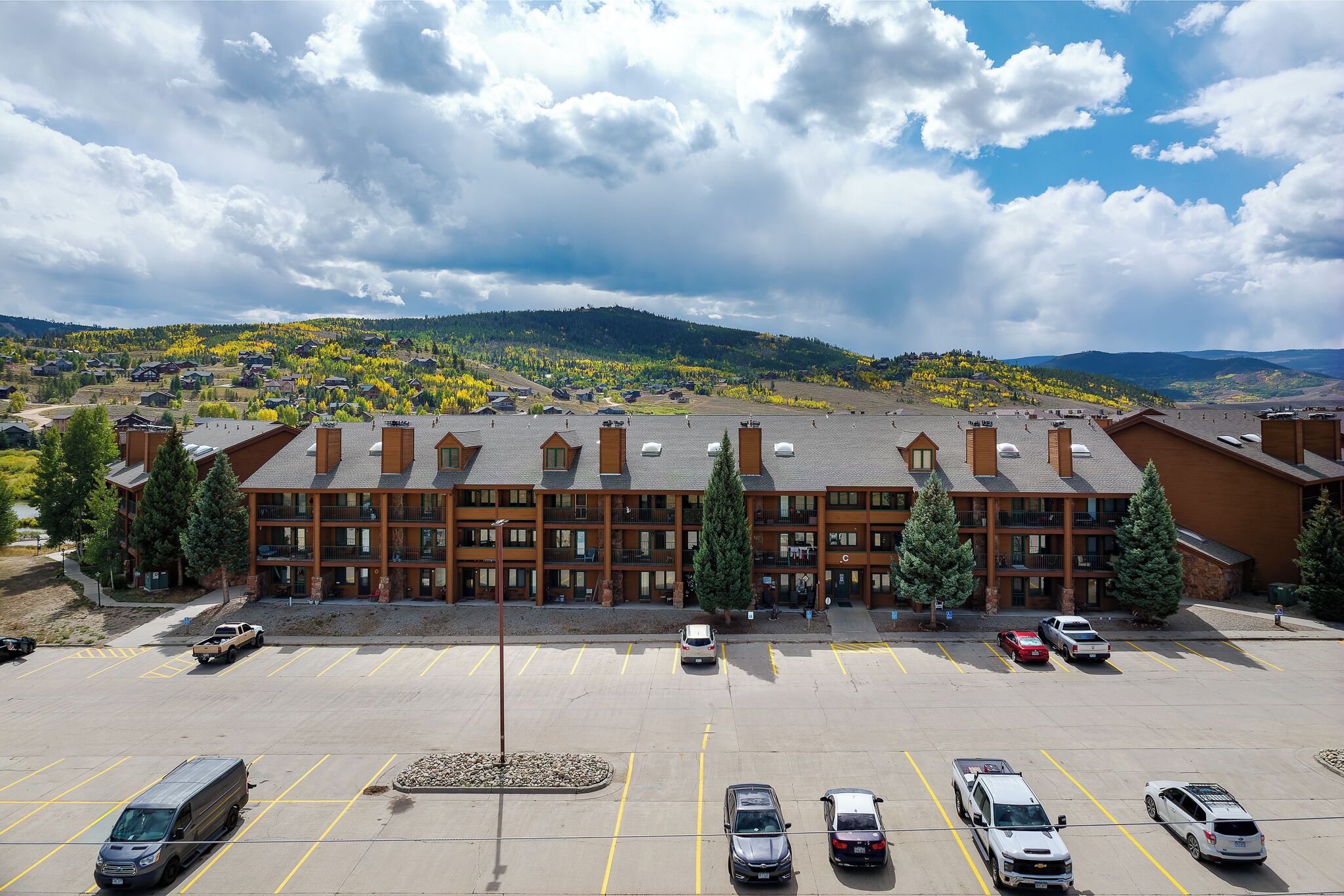 A multi-story hotel with a parking lot, surrounded by a mountainous landscape.