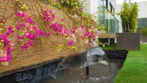 A modern building with a water feature and lush greenery. - Belfast studio-Blue Waters Property. (Accra)