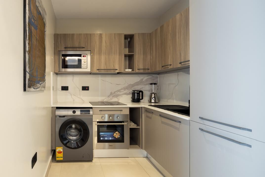 A compact kitchen with a built-in washer and dryer, a microwave, a coffee maker, and a stove.