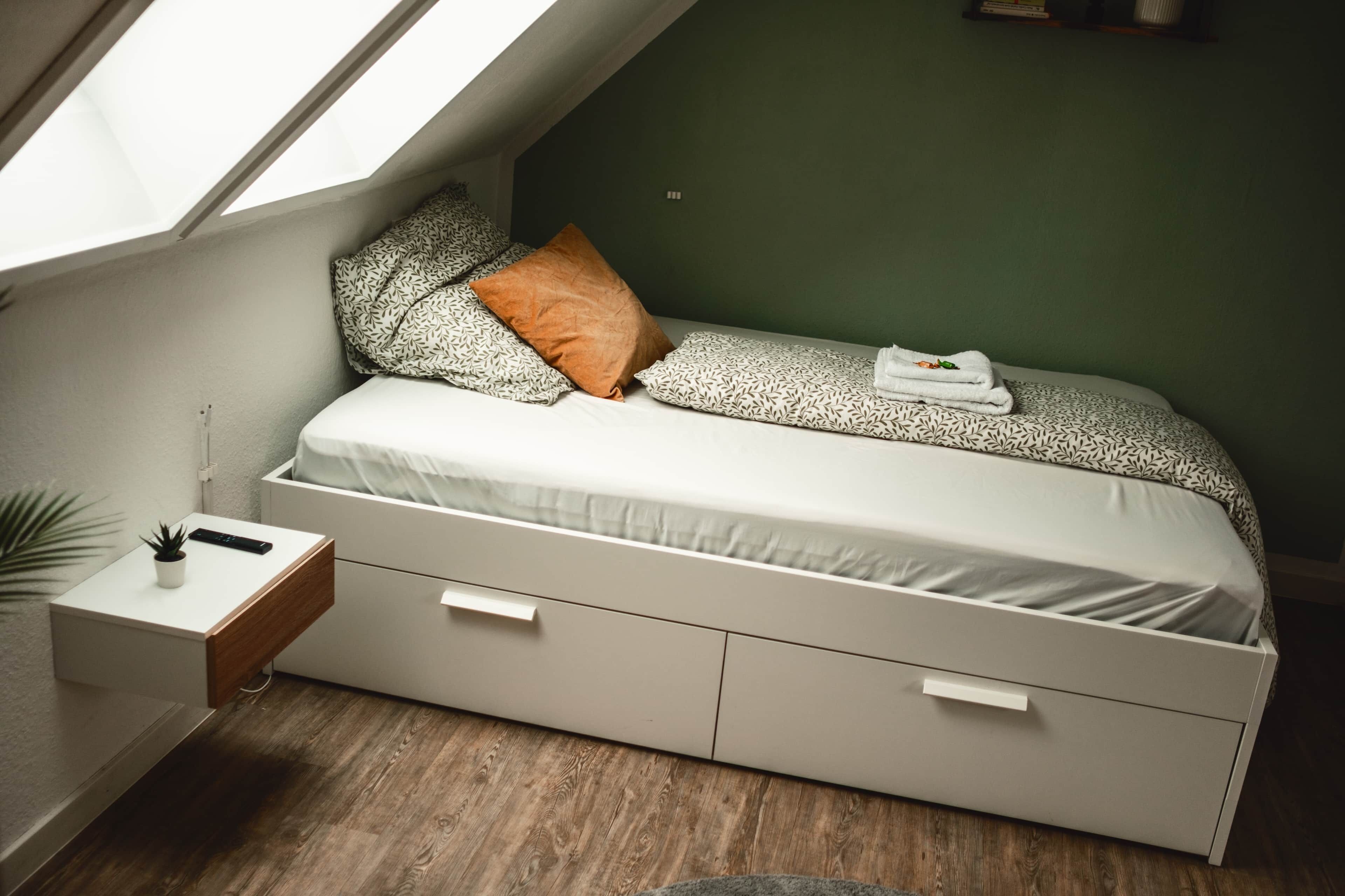 Ein Schlafzimmer mit Schlafpodest, einem Nachttisch mit Pflanze und einem kleinen Schreibtisch.