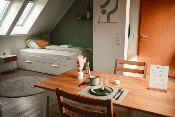 Une chambre moderne et compacte, dotée d’un lit en mezzanine, d’une table à manger avec des chaises, d’un petit tapis et d’un présentoir à menus.