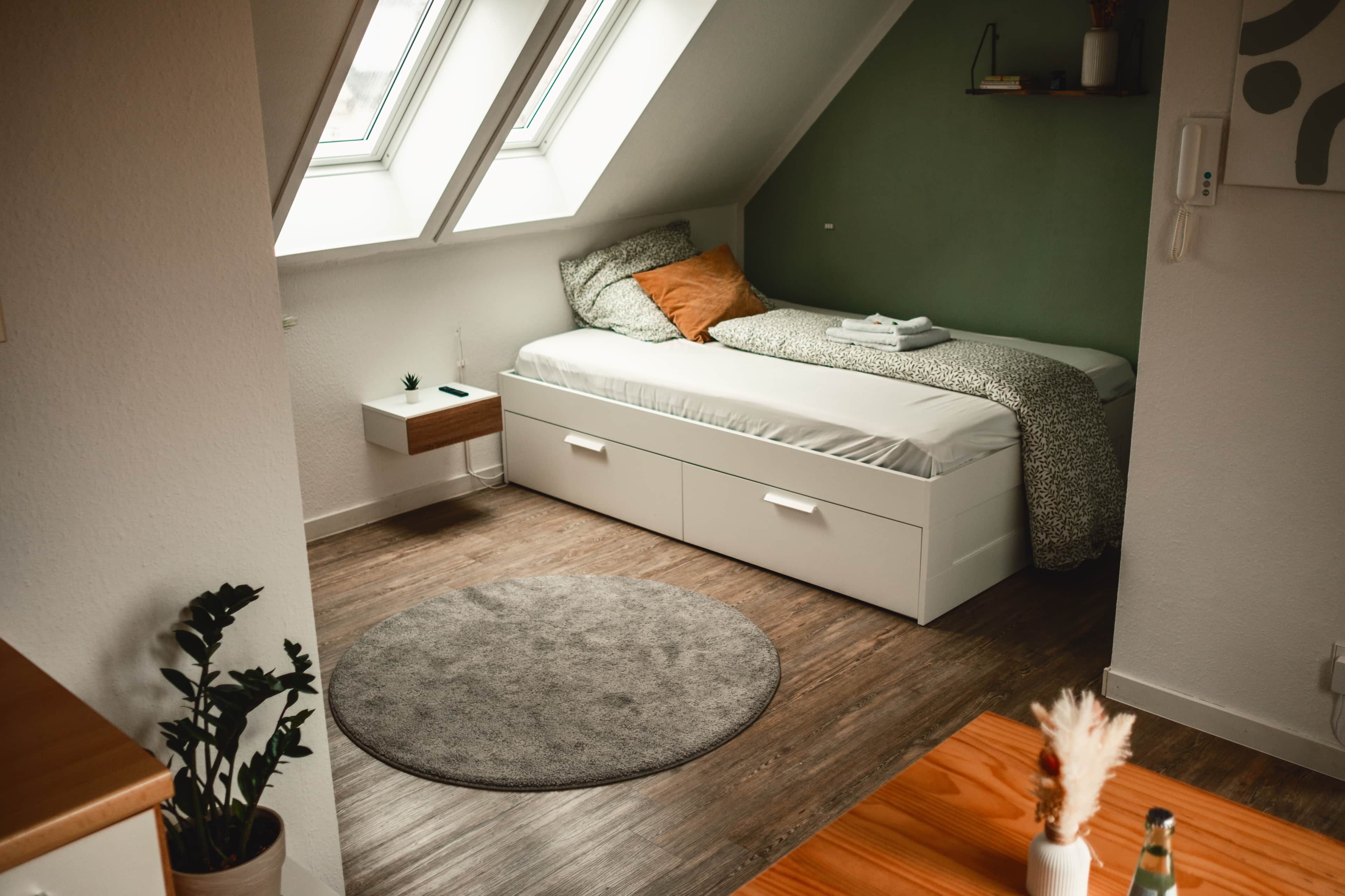 Un dormitorio moderno con cama tipo litera, tragaluz y una mesita de noche pequeña.