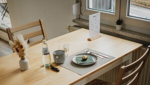 Ein Holztisch mit einer Speisekartenständer, einer Flasche, einer Tasse und einem Teller mit einer kleinen Schale.