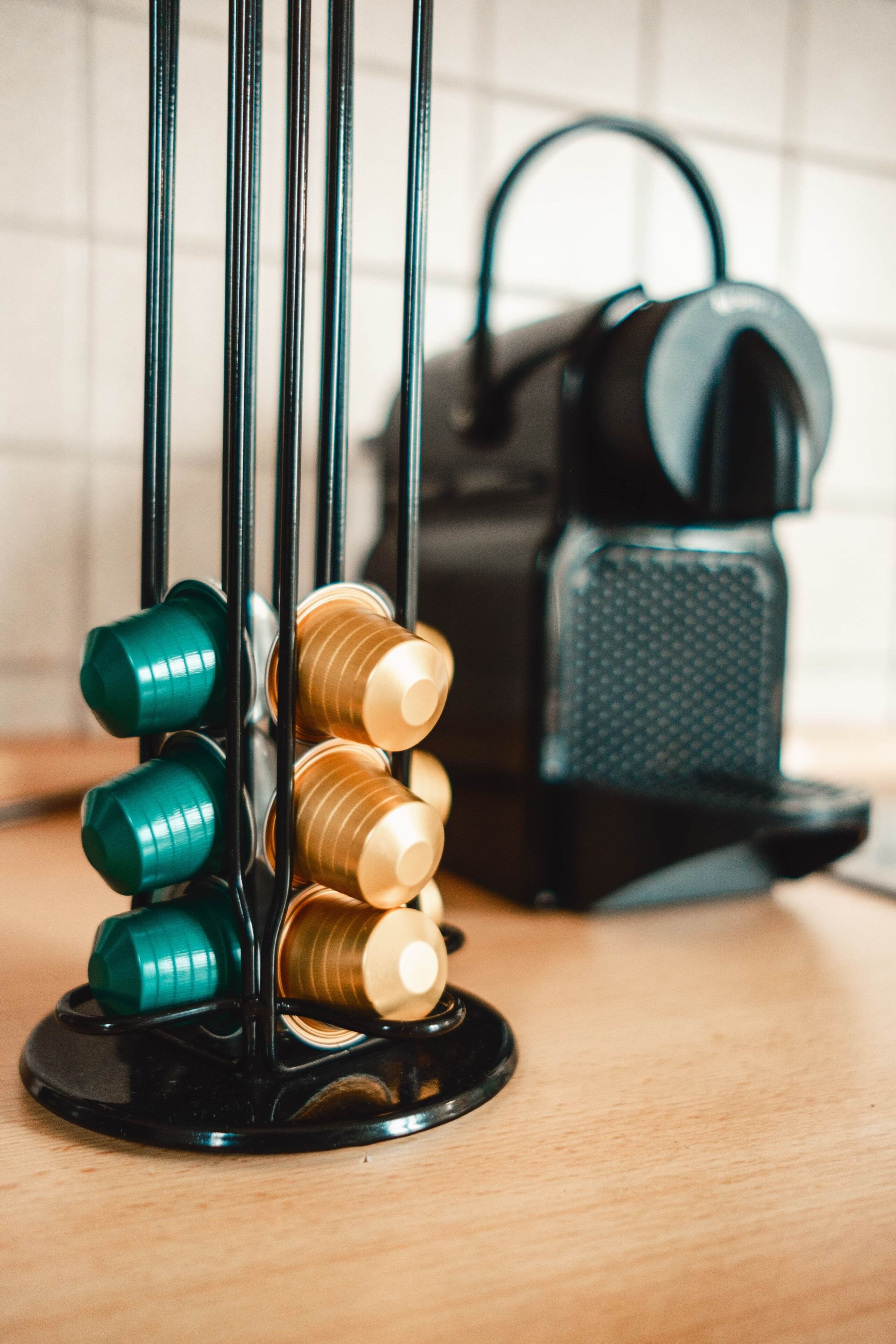 A black bottle holder with green and gold bottles on a wooden surface.