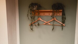 Eine hölzerne Bank mit Fußmatte vor einer an der Wand befestigten Holzablage mit Pflanzen.