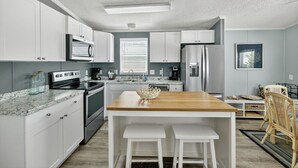 A modern kitchen with white cabinets, a wooden island, and stainless steel appliances. - Limited-Time Spring & Summer Deals: Dog-Friendly 2BR Beach Getaway (Jensen Beach)