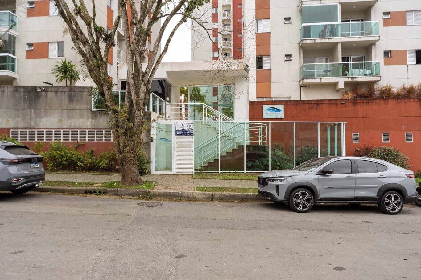 A modern building with a glass entrance, a staircase, and a parked car.