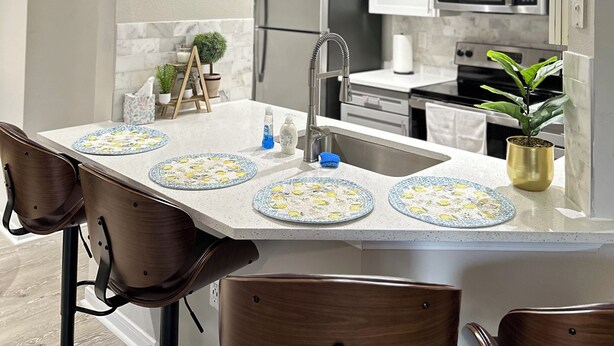 A modern kitchen with white cabinets, stainless steel appliances, and a central island with a sink and stools.