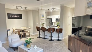 A modern living room with a dining area, kitchen, and bar seating.