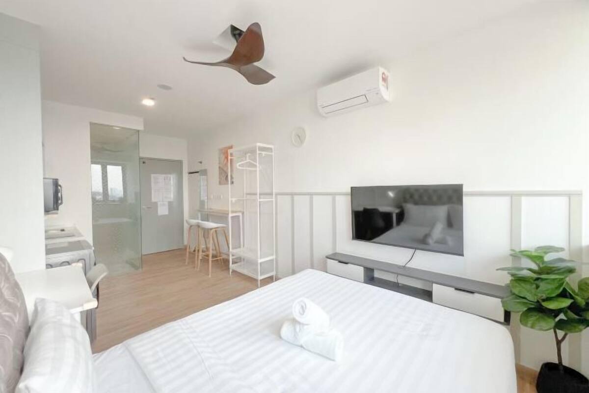 A modern hotel room with a bed, a TV, a desk, and a walk-in closet.