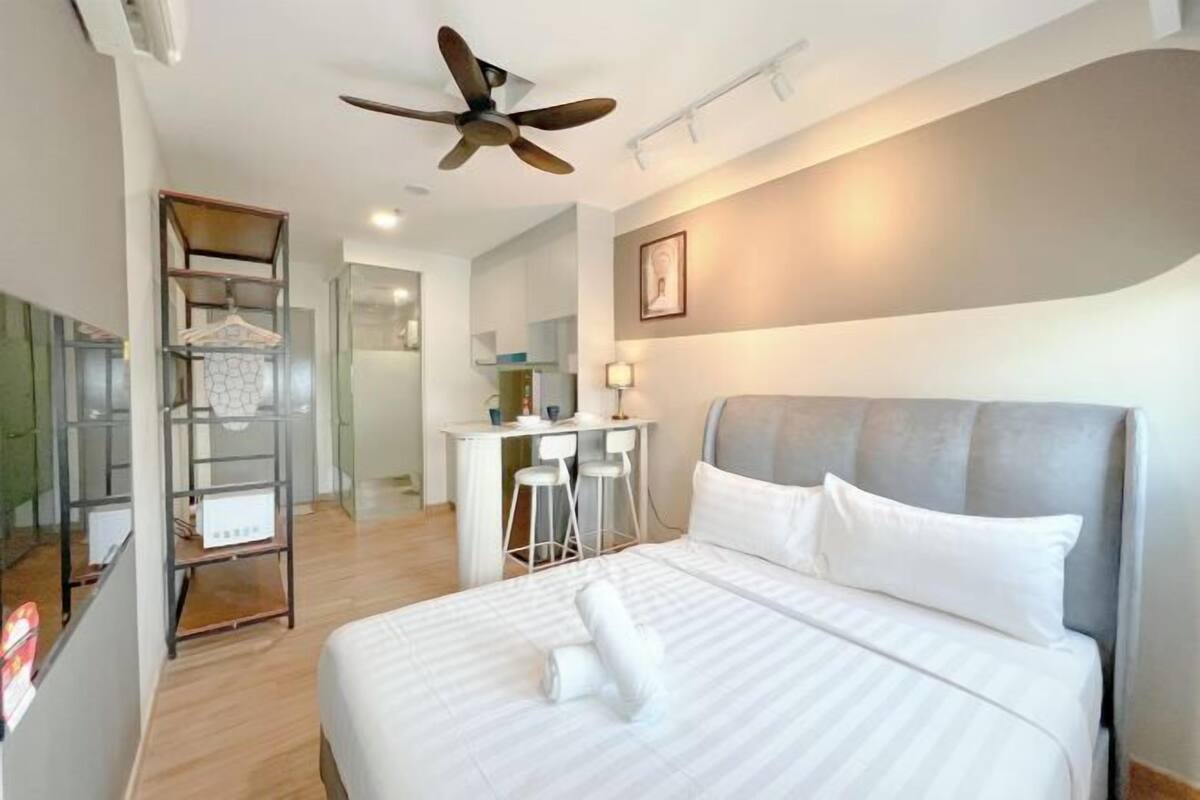 A hotel room with a bed, a desk, a chair, a ceiling fan, and a wardrobe.