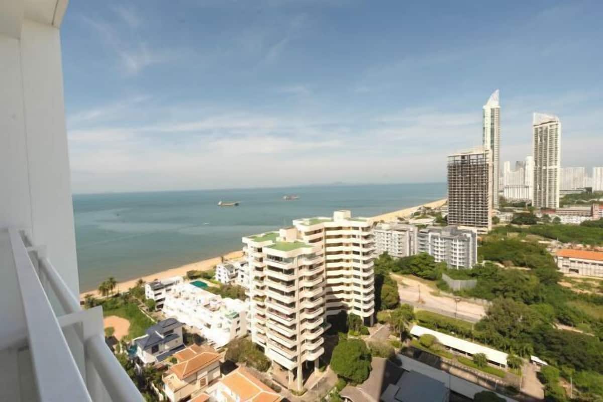 A coastal cityscape with high-rise buildings, a beach, and a clear sky.