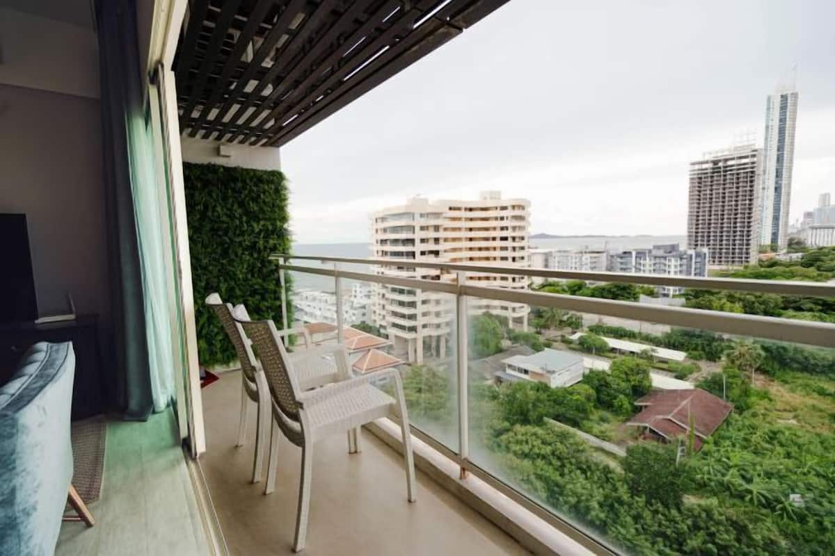 A balcony with a view of a cityscape, including buildings and greenery.