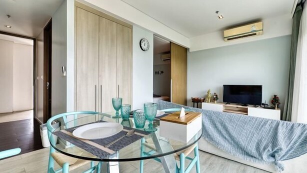 Um espaço de estar moderno com uma mesa de jantar de vidro, uma televisão e um sofá.