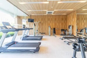 A gym with treadmills, weight machines, and a television screen. - Residence by Hello Pattaya at Veranda (Sattahip)