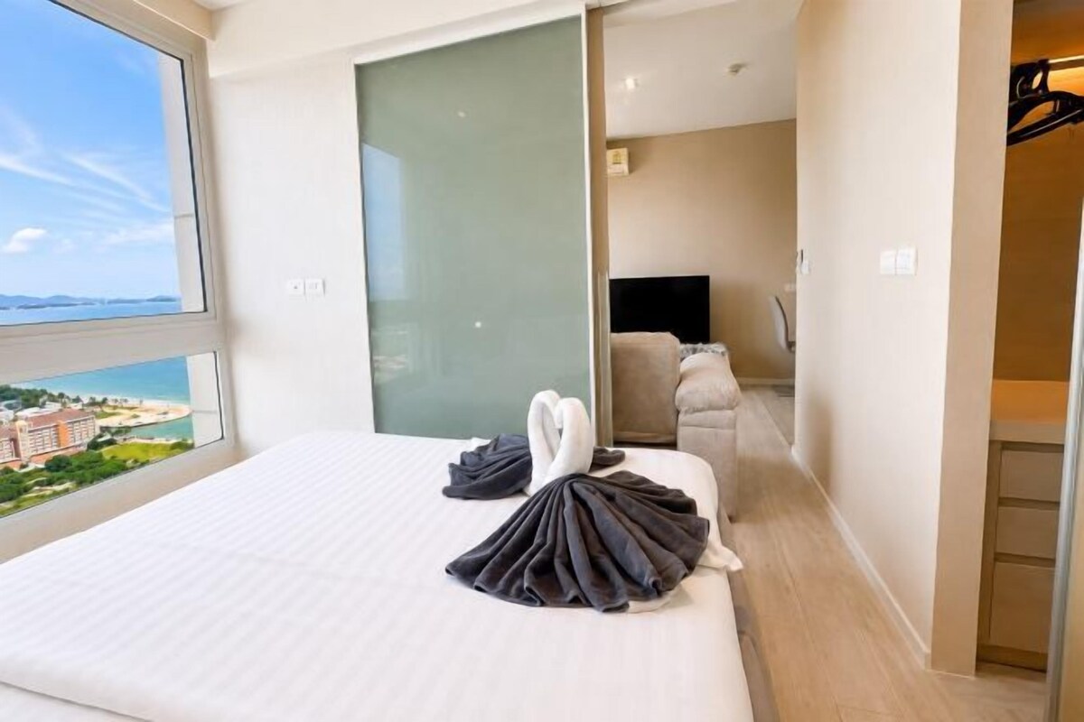 A hotel room with a bed, a view of the sea, and a sliding door leading to a bathroom.