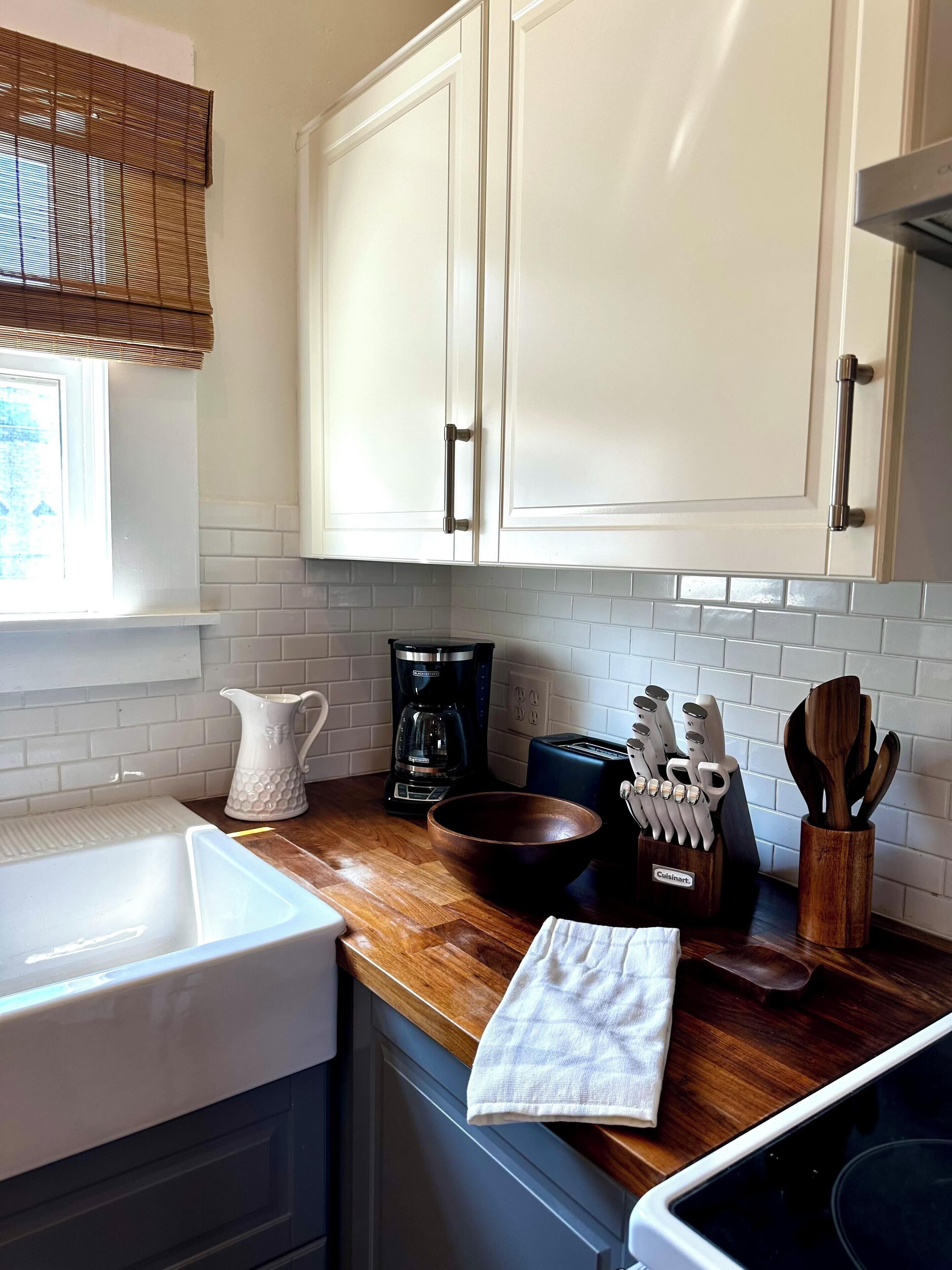 A kitchen with white cabinets, a coffee maker, a toaster, and wooden utensils.