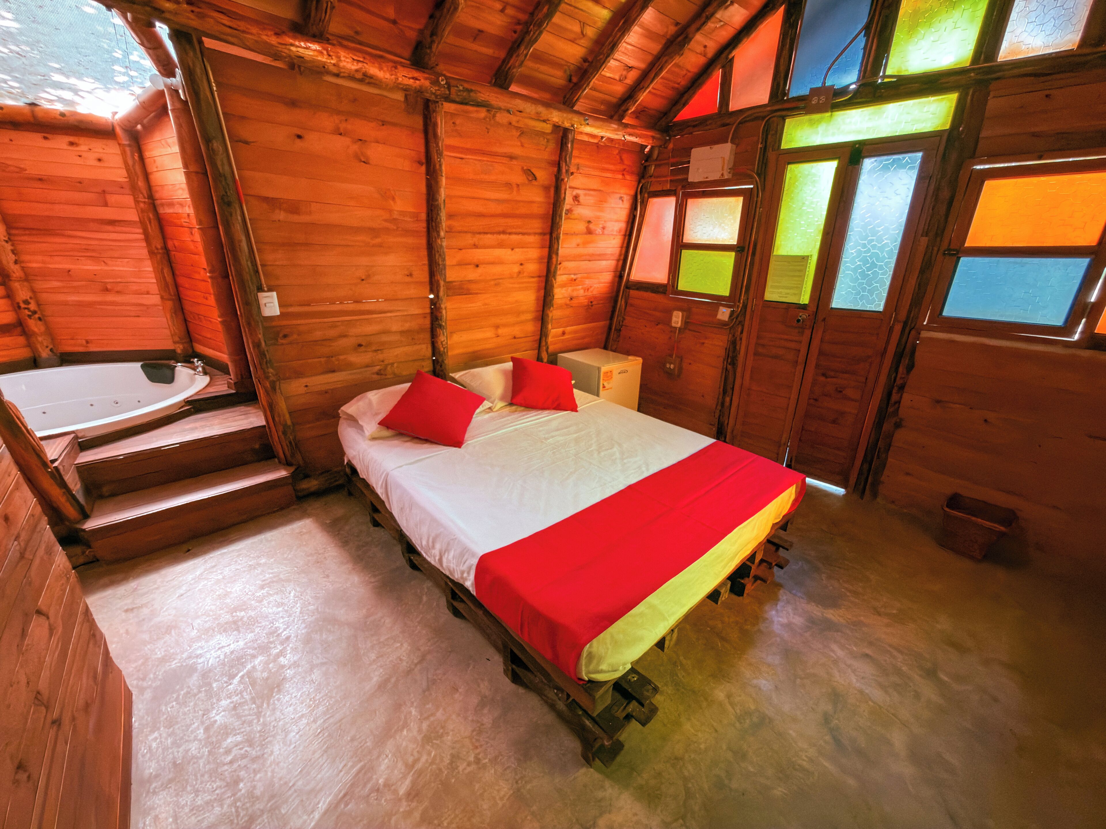 Una habitación de cabaña de madera con una cama, una mesita y una ventana con vistas.