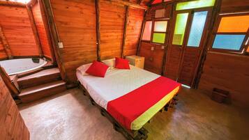 Una habitación de cabaña de madera con una cama, una mesita y una ventana con vistas.