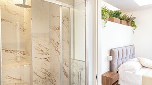 A modern bathroom with a glass-enclosed shower, marble tiles, and a bedside plant shelf. - Spacious BnB with 3 rooms and kitchen, a few steps from St. Peter's (Roma)