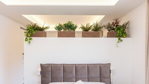 A bedroom with a tufted headboard, a bed with white linens, two bedside tables, and a skylight above a shelf with plants. - Spacious BnB with 3 rooms and kitchen, a few steps from St. Peter's (Roma)