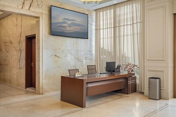A reception desk in a lobby with marble walls, a framed picture, and a trash bin. - Laos Guiting Hunan Grand Hotel (Free Airport Transfer with Reservation) (Vientiane)
