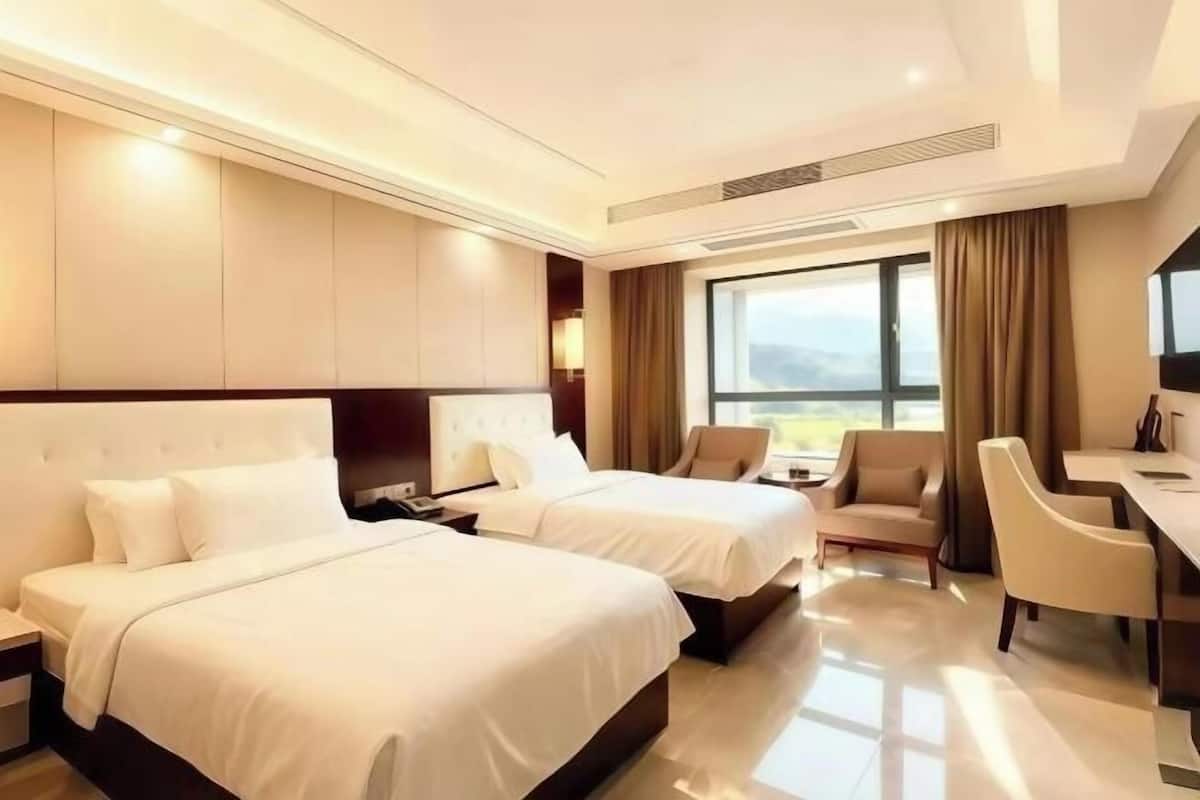 A hotel room with two beds, a desk, and a chair.
