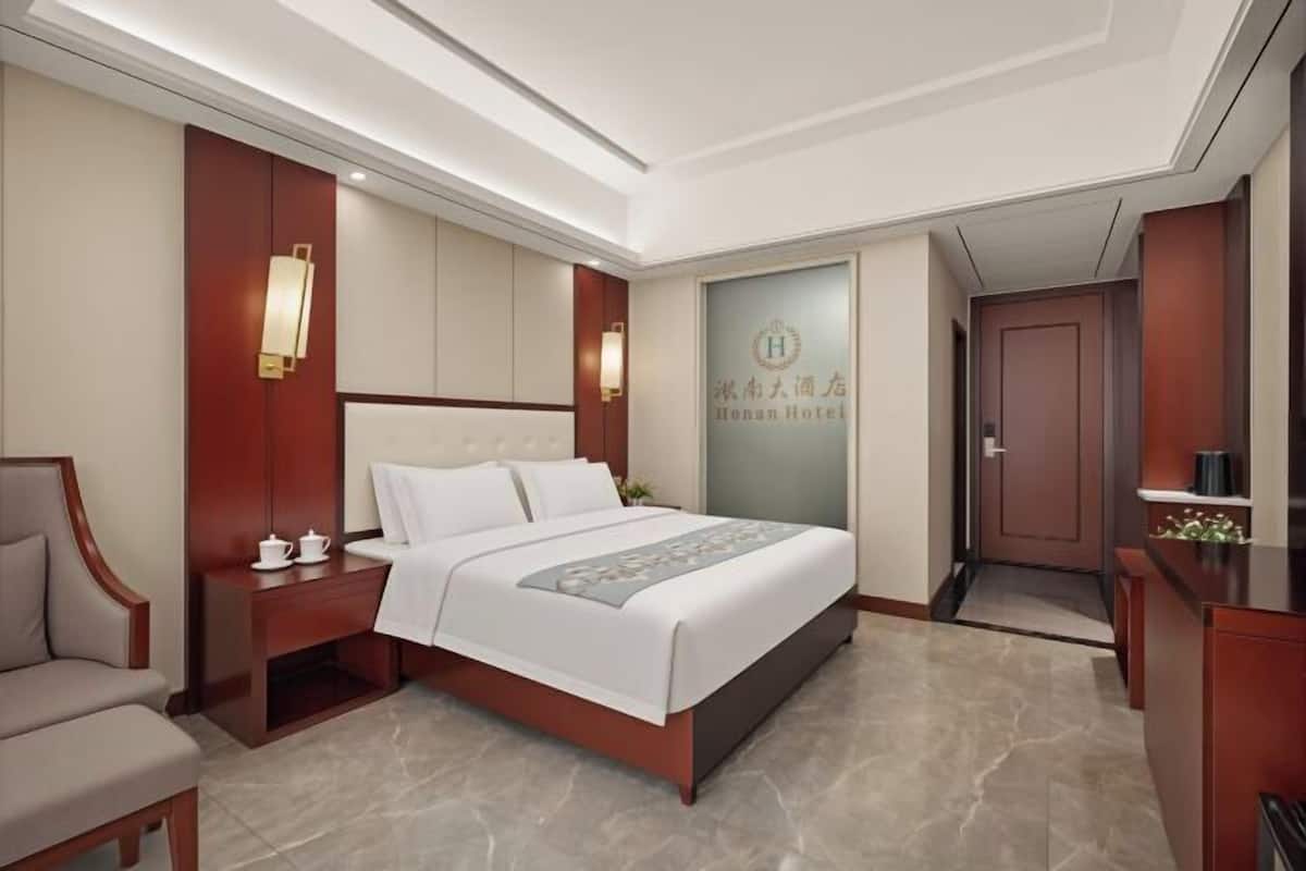 A hotel room with a large bed, bedside tables, a desk, and a wardrobe.