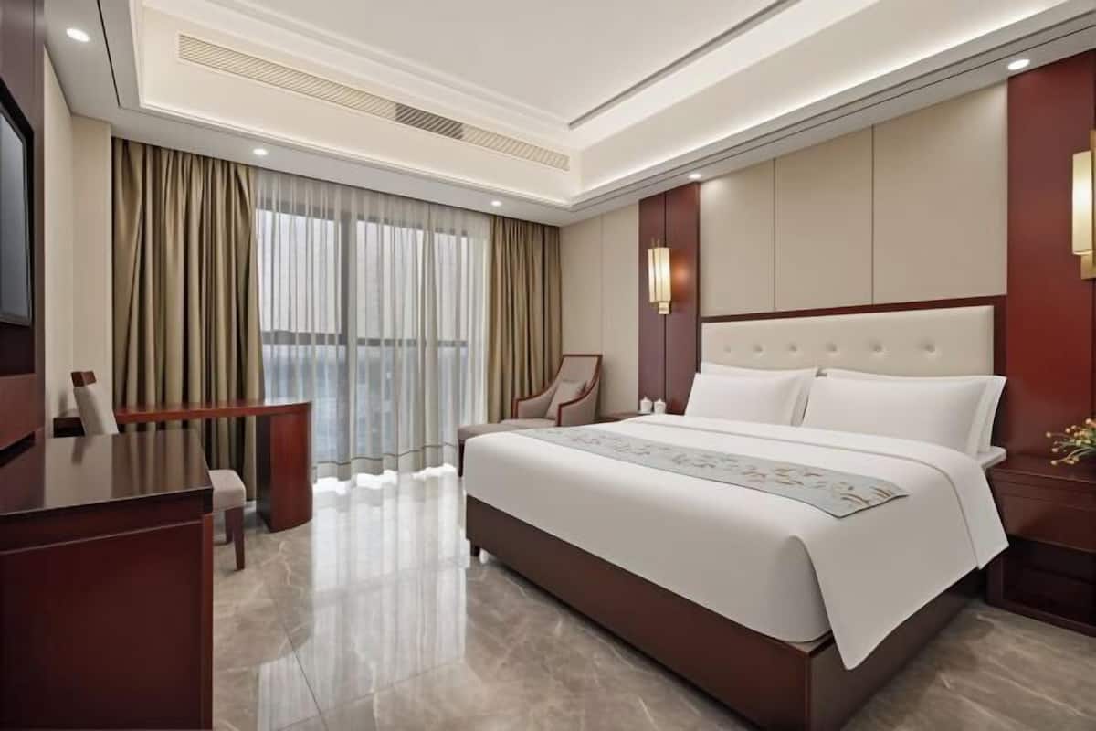 A hotel room with a large bed, a desk, and a chair.