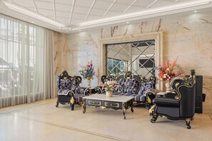 Ein luxuriöses Zimmer mit Marmorboden, einem großen Fenster mit Vorhängen und kunstvollen Möbeln, darunter zwei Sofas und ein Couchtisch.