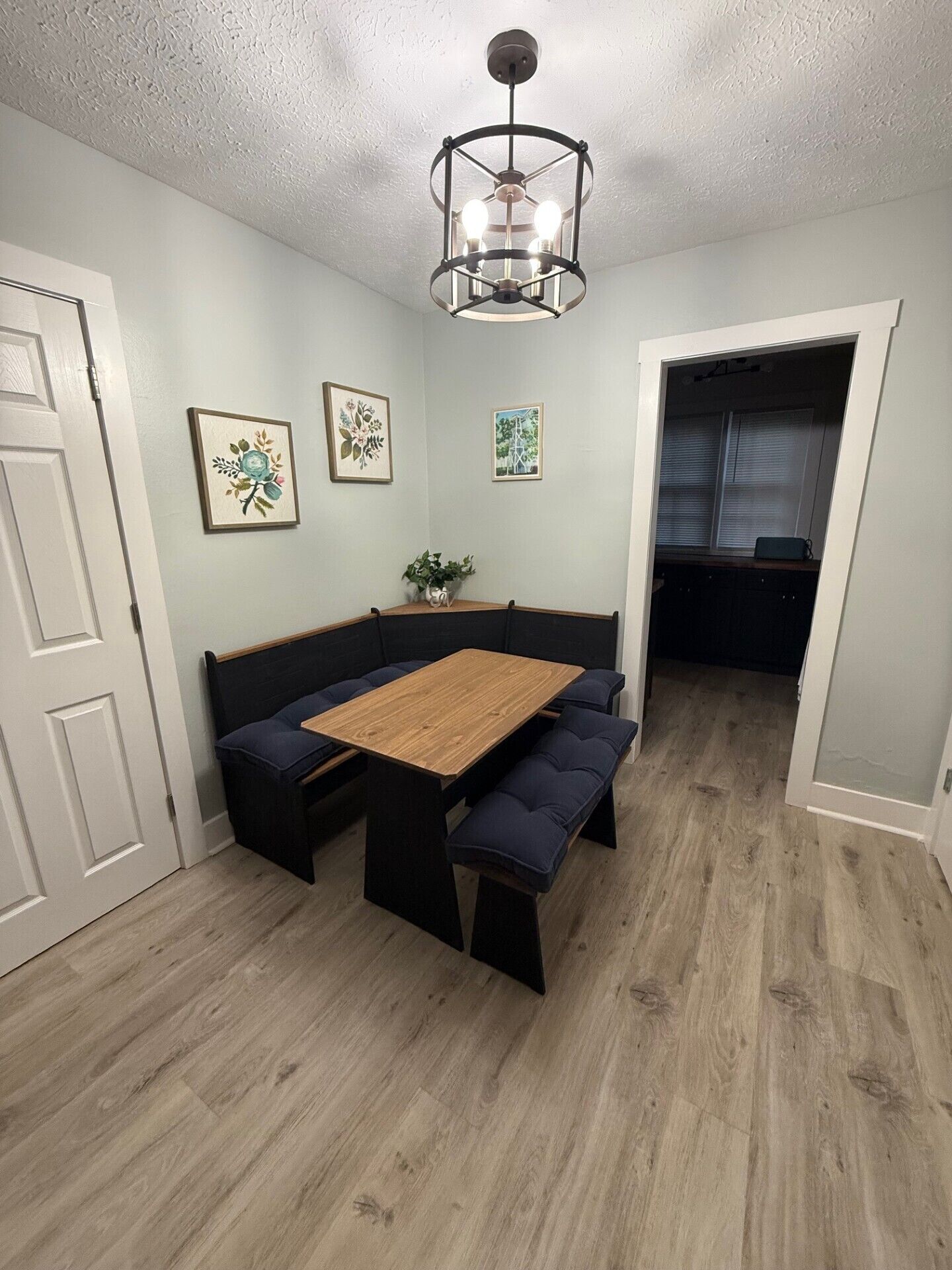 A dining area with a wooden table and benches, a ceiling light fixture, and framed artwork on the walls.