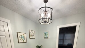 Uma área de refeições com uma mesa de madeira e bancos, um lustre e quadros nas paredes.