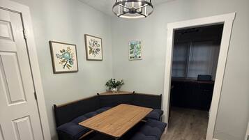 A dining area with a wooden table and benches, a ceiling light fixture, and framed artwork on the walls.