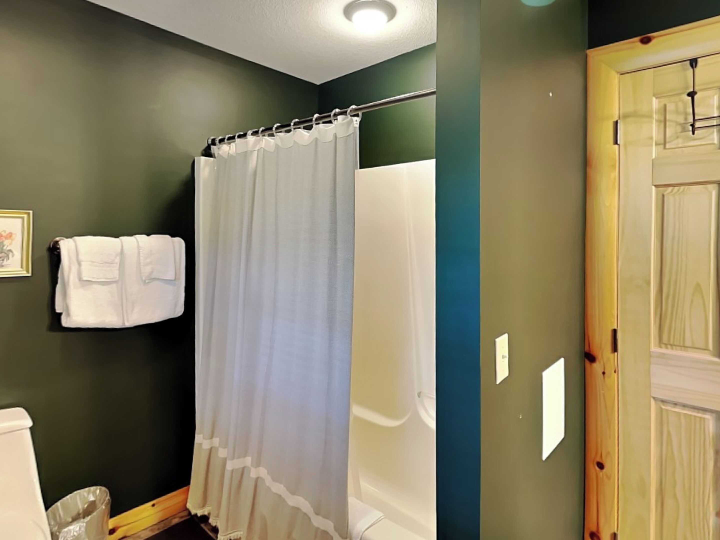 A bathroom with a shower curtain, a toilet, and a towel rack with towels.