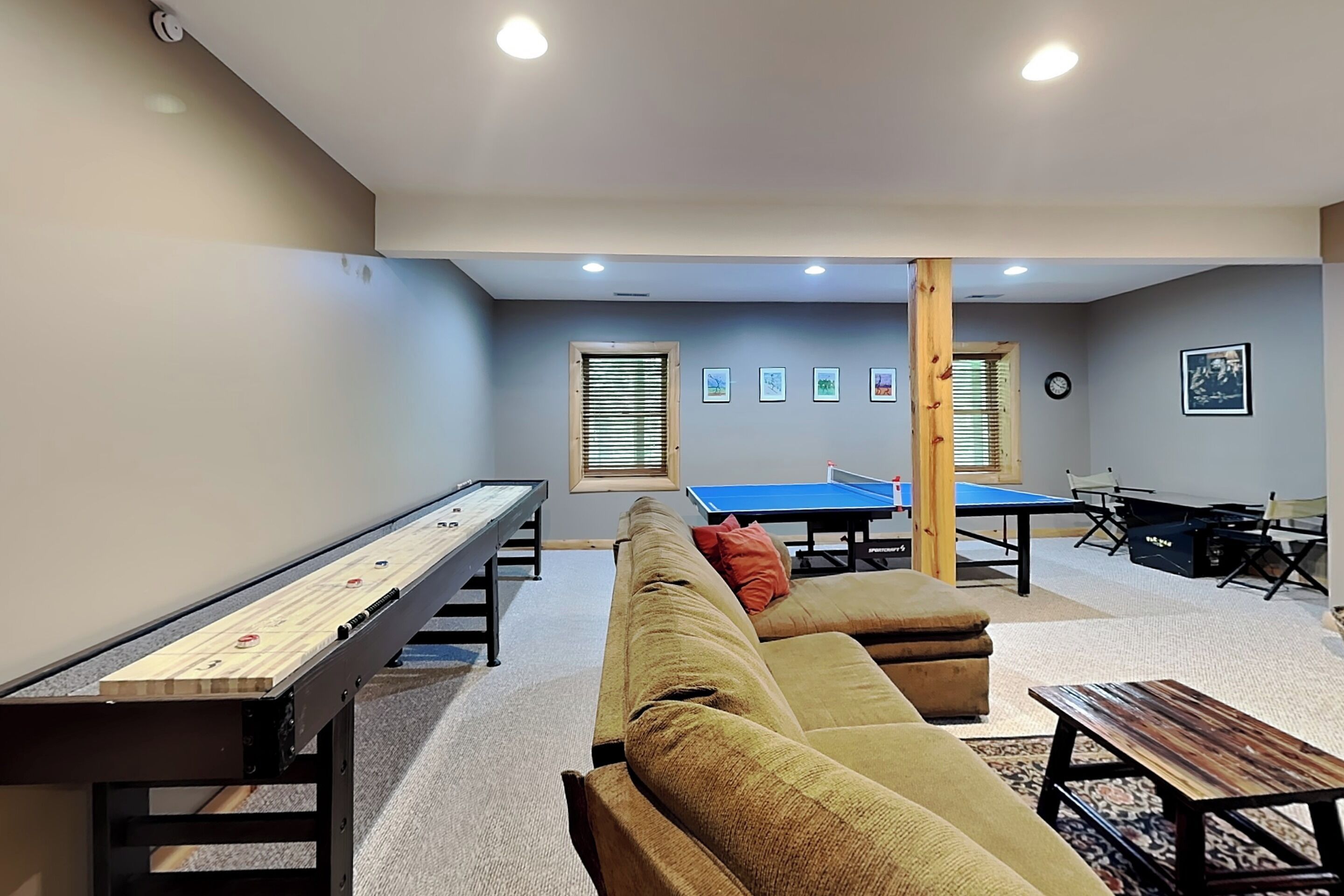 A room with a pool table, ping pong table, and shuffleboard table.