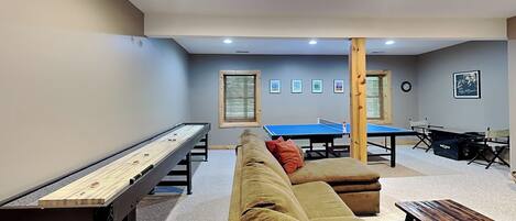 A room with a pool table, ping pong table, and shuffleboard table.