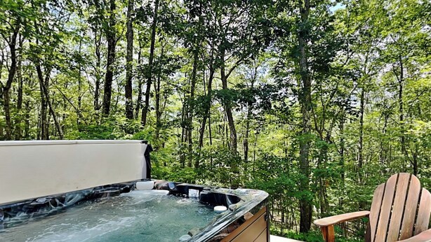 Un bain à remous sur une terrasse en bois, entouré d’arbres.