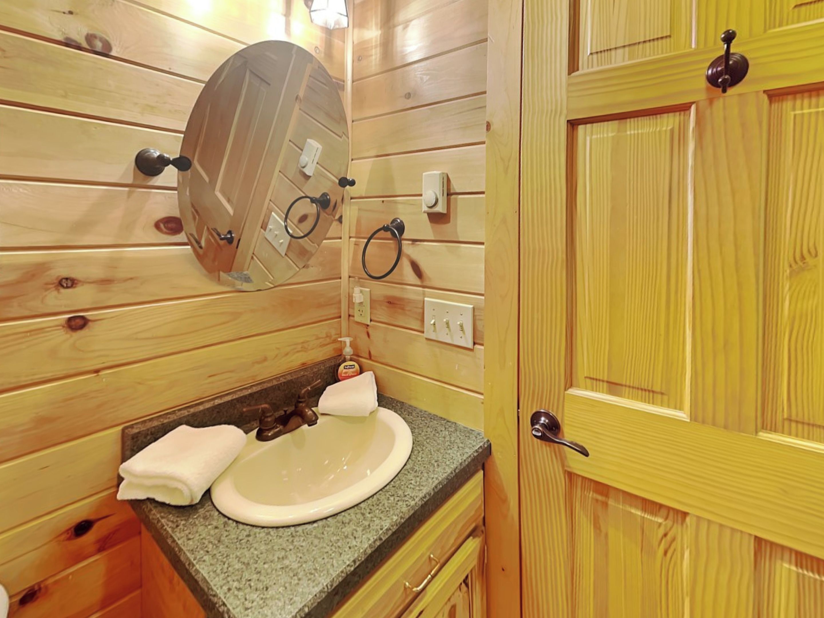 Ein Badezimmer aus Holz mit Waschbecken, Handtuch und Spiegel.