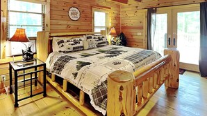 A cabin-style bedroom with a wooden bed, a ceiling fan, and a sign that reads "cabin sweet cabin". - Log Heaven by Taylor Made Deep Creek (Oakland)