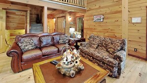 A wooden cabin interior with a double balcony, two sofas, a coffee table, and a sign indicating the cabins are closed. - Log Heaven by Taylor Made Deep Creek (Oakland)