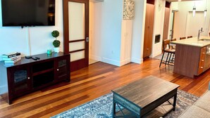 A modern living room with a flat-screen TV, wooden entertainment unit, and a coffee table. - Luxury 2BR/2BA Channelside Condo- Pool, Sauna, Gym + Balcony (Tampa)