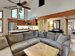 A modern living room with a sectional sofa, a wooden coffee table, and a ceiling fan.