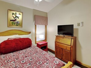 A bedroom with a bed, a television on a wooden dresser, a window with blinds, and a ceiling fan. - Somewhere by Taylor Made Deep Creek (Oakland)