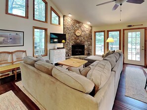 A living room with a stone fireplace, a television, and a large window. - Somewhere by Taylor Made Deep Creek (Oakland)