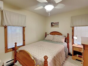 Ein Schlafzimmer mit einem Holzbett, einem Deckenventilator und einem Nachttisch mit Lampe.