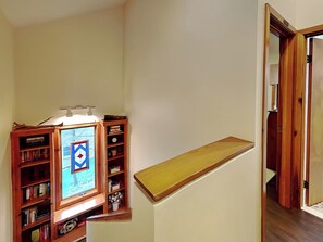 A staircase with a wooden handrail, a wooden bookshelf filled with books, and a framed picture on the wall. - Somewhere by Taylor Made Deep Creek (Oakland)