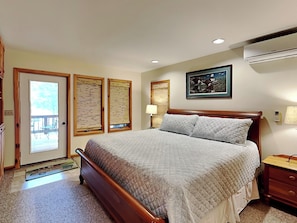 A bedroom with a wooden bed, a door with a view, two wall-mounted air conditioning units, and a framed picture on the wall. - Somewhere by Taylor Made Deep Creek (Oakland)