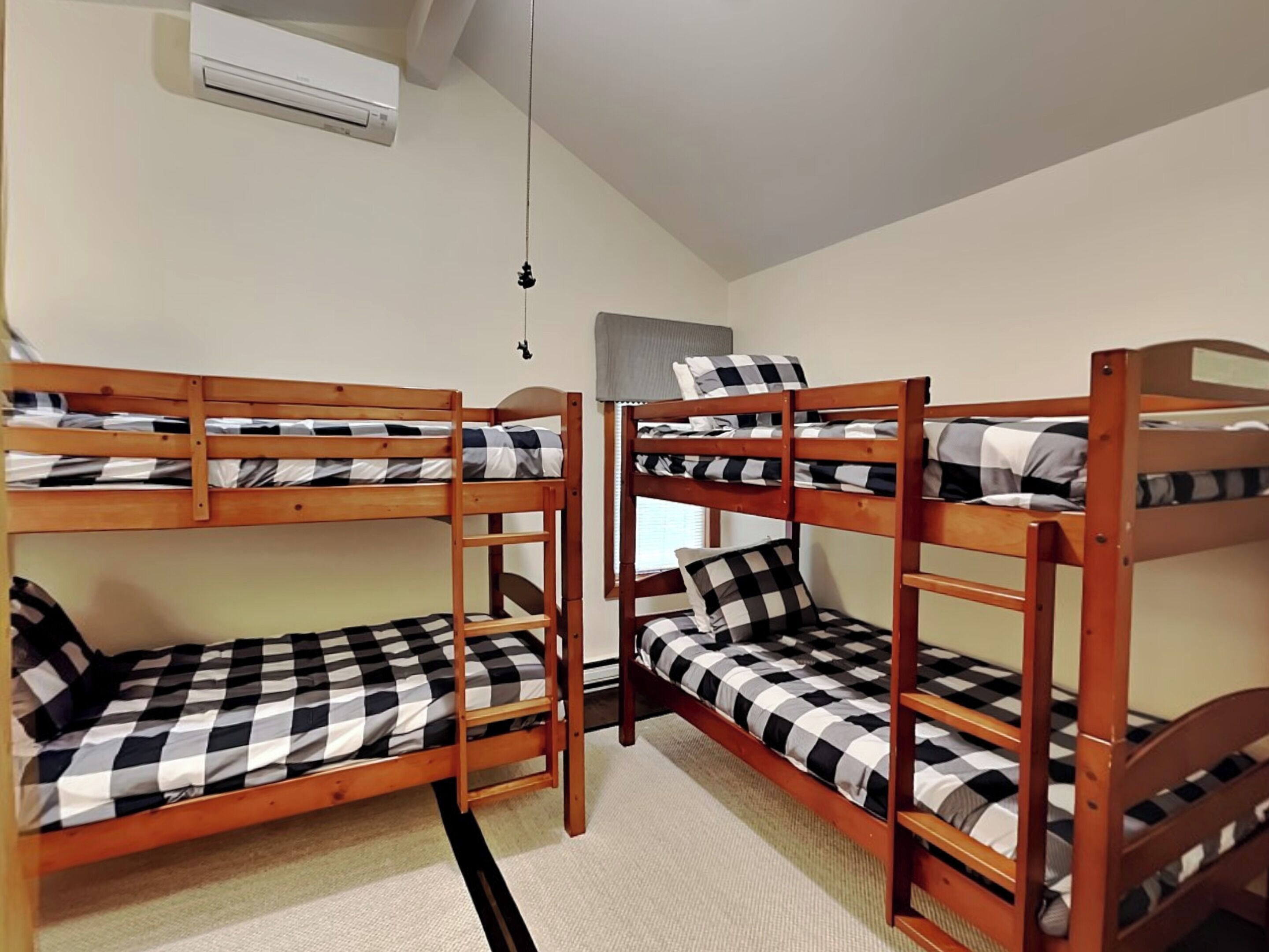 A dormitory room with bunk beds, a ceiling fan, and a window.