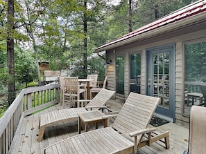 A wooden deck with lounge chairs and a table, surrounded by trees. - Somewhere by Taylor Made Deep Creek (Oakland)